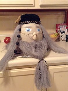 a doll with long gray hair sitting on top of a counter