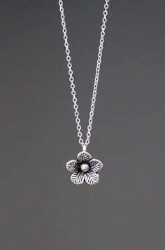 A lovely three dimensional Bali Silver flower charm simply dangles from a silver chain.  Choose from a 1mm silver chain with a silver spring ring clasp, or a 1.5mm silver chain with a silver lobster clasp. Each chain measures 16" with an extension to 18".  Please send a message if a different length chain is desired. Great as a layering piece or wonderful by itself.  Multiple quantities may be ordered.  Bali Silver flower: 10x12mm Total length of charm: 1/2" Silver chain: 1mm or 1.5mm All silver Dainty Silver Charm Necklace With Flower Pendant, Nickel-free Silver Flower Charm Necklace, Delicate Silver Charm Necklace With Flower, Sterling Silver Flower Charm Necklaces, Sterling Silver Charm Necklace With Flower Charm, Delicate Silver Flower-shaped Charm Necklace, Delicate Silver Flower Shape Charm Necklace, Silver Delicate Flower Charm Necklace, Delicate Silver Flower Charm Necklace