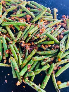 green beans with bacon on top and seasoning in the middle, sitting on a black surface