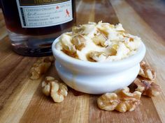 a white bowl filled with walnuts next to a bottle of whiskey