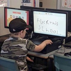 a young boy sitting in front of two computer monitors with the word fluck this school written on them