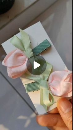 a person is holding up a card with two bows on it and the ribbon has been folded