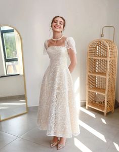 a woman standing in front of a mirror wearing a white dress and smiling at the camera