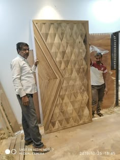 two men standing next to each other in front of a wooden door with diamond designs on it