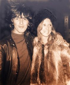 two people standing next to each other wearing fur coats