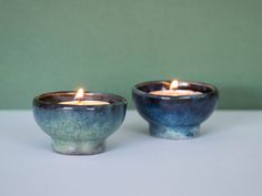 two blue bowls with candles in them on a table