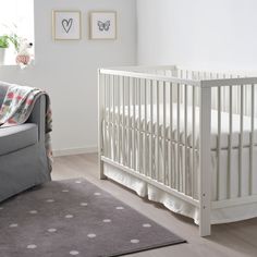 a baby's room with a white crib and gray rug on the floor