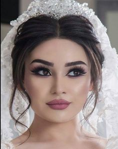 a woman wearing a bridal gown and veil with flowers on her head, posing for the camera