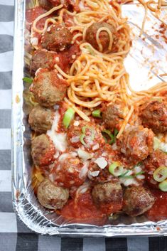 meatballs and spaghetti in a pan on a checkered table cloth