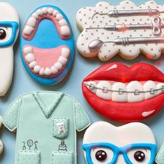 some cookies are decorated like teeth, shirts and dental instruments on a blue tablecloth