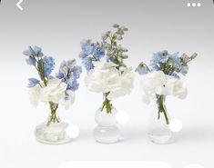 three clear vases with blue and white flowers in them