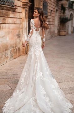 a woman in a white wedding dress standing on the street with her back to the camera