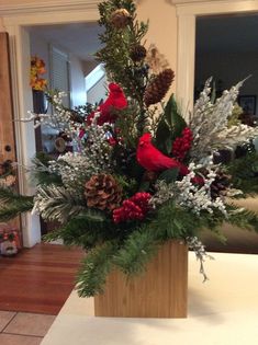 a vase filled with pine cones and red birds