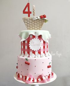 a three tiered cake with red and white checkered icing, topped with a wicker basket