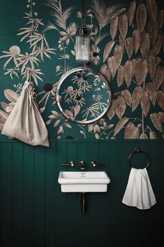 a bathroom with green walls and floral wallpaper in the corner, along with a white sink