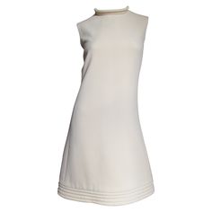 A fabulous off white wool dress by Pierre Cardin. It is an A line sleeveless dress with a stand up collar and hem highlighted with rows of top stitching around their circumferences. It is lined in off white and has a center back hand sewn metal zipper. Fits sizes Small, Medium. Marked US size 6. Bust 36" Waist 30" Hips 39" Length 38" Classic White A-line Sleeveless Dress, Classic White Sleeveless Dress, Classic Wool A-line Dress, Chic Cream High Neck Dress, Chic High Neck Cream Dress, Classic A-line Wool Dress, Vintage Sleeveless Cream Mini Dress, Vintage Cream Sleeveless Mini Dress, Fitted Wool Dress In Beige