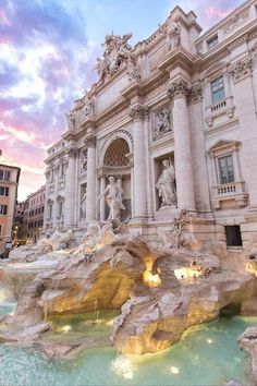 an ornate building with statues and fountains in front of it at sunset or sunrise time