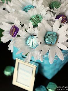 a blue vase filled with white flowers and chocolates