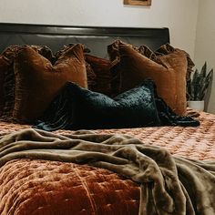 a bed with pillows and blankets on top of it next to a plant in a vase