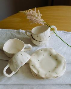 two white cups and saucers with sprinkles sit on a table next to a flower