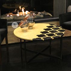 two glasses are sitting on a coffee table in front of a fire place with candles