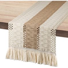 a table runner with fringes on it and a wooden table top in the background