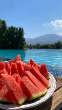 slices of watermelon are on a white plate near the edge of a pool