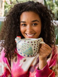 a woman is holding a tea cup and smiling