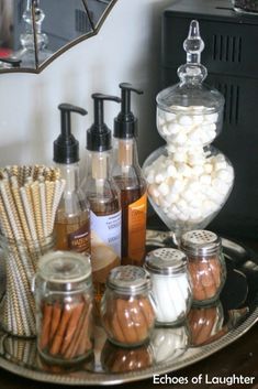 there are many different types of soaps and lotions on the tray in front of the mirror