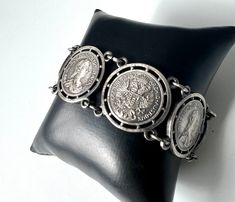 This charming vintage costume jewelry bracelet is a beautiful testament to times gone by. Made from silver-tone metal, it features six artfully designed imitation coins reminiscent of the era of Maria Theresa. The bracelet is approximately 21 cm long in total, but can be worn shorter for a more comfortable fit. With a width of approximately 2.5 cm, this bracelet adds a touch of elegance and nostalgia to any wrist. Material: Silver tone metal Design: Imitation coins with Maria Theresa image Lengt Maria Theresa, Artfully Designed, Coin Bracelet, Jewelry Bracelet, Traditional Jewelry, Metal Design, Vintage Costume Jewelry, Vintage Costumes, Chain Link Bracelet