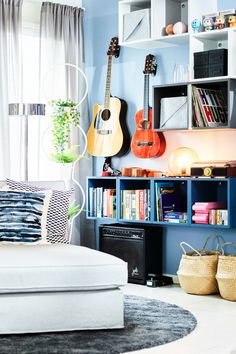 a living room filled with lots of books and guitars on the wall next to a couch