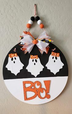 a sign that says boo on it with three ghost heads hanging from the front and back