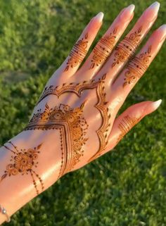 a hand with henna on it in the grass