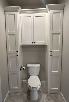 a white toilet sitting inside of a bathroom next to two closet doors on the wall