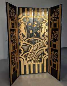 an art deco door is shown in black and gold with designs on the front panel