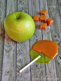 an apple and some pieces of fruit on a wooden table next to a stick of candy