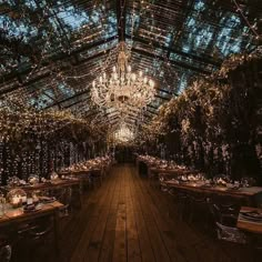 an indoor dining area with chandelier and wooden tables set up for dinner in the evening