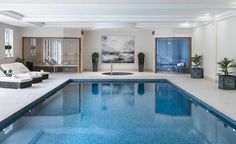 an indoor swimming pool with blue water and plants in the middle, surrounded by white walls