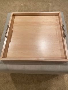 a wooden tray sitting on top of a gray ottoman