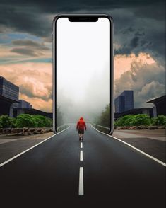 a person walking down the middle of an empty road with a giant phone in front of them