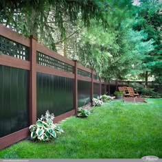 a wooden fence with green grass and trees in the background