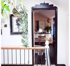 an open door leading to a living room with plants on the wall and pictures hanging above