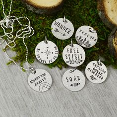 six hand stamped necklaces with words on them sitting next to some moss and stones