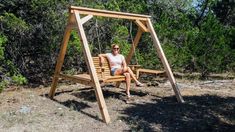 a woman sitting on a wooden swing in the woods