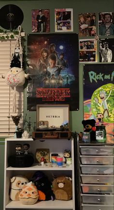 a room with posters and stuffed animals on the wall next to a book shelf filled with books