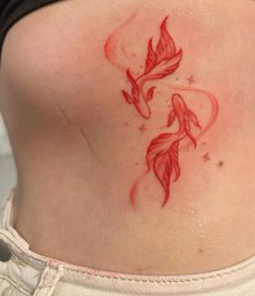 a woman's lower back tattoo with two fish on her stomach and stars in the background