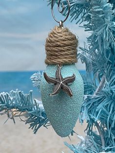 a starfish ornament hanging from a christmas tree on the beach with blue tinsel