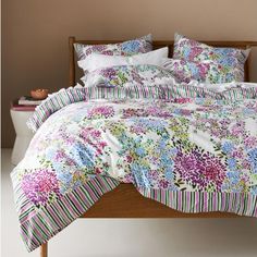 a bed with colorful flowers and striped sheets