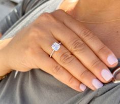 a woman's hand with a ring on her finger and a diamond in the middle