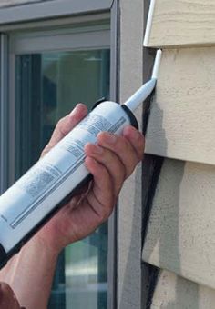 a person is holding a window sealer in their hand and opening it to the side of a house